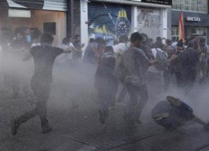 Anti-government protesters take cover as riot police use water cannon to disperse them at Taksim square in Istanbul