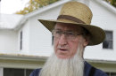FILE - In this Oct. 10, 2011 file photo, Sam Mullet Sr. stands in the front yard of his home in Bergholz, Ohio. In the stern, self-regulating world of the Amish, those who act out time and again by wearing the wrong clothing, going to movies or otherwise flaunting the church's doctrine can find themselves utterly alone. At the root of Amish hair-cutting attacks in Ohio and the federal hate crime trial that followed, prosecutors say, was a dispute over religious differences and a decision by Amish bishops to overrule Mullet, the leader of a breakaway group who had shunned his former followers. (AP Photo/Amy Sancetta, File)