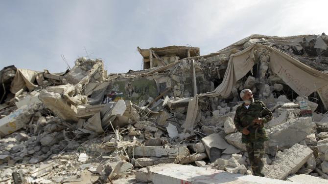 A Libyan fighter walks amidst rubble