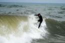 A surfer rides a wave after Hurricane Arthur in Kitty Hawk