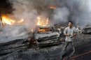 In this picture taken on Thursday August 15, 2013, A Lebanese citizen stand next to burned cars and shops at the site of a car bomb explosion, in an overwhelmingly Shiite area and stronghold of the Lebanese militant group Hezbollah, at the southern suburb of Beirut, Lebanon. Car bombings and rocket attacks targeting Hezbollah strongholds south of Beirut have shaken the militant group and its Shiite supporters to the core, bringing a sense of fear and unease to a community that has been largely spared the violence plaguing the rest of the country. (AP Photo/Hussein Malla)
