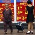 File picture of shoppers walking past and look at a board displaying food prices at a shopping mall in central Beijing
