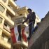 A young Egyptian man holds a national flag while standing on a rooftop between Tahrir Square and the Interior Ministry in Cairo, Egypt, Thursday, Nov. 26, 2011. Egyptian medical officials say that one demonstrator has been killed outside the country's Cabinet building, where protesters have camped overnight to prevent the entrance of the country's newly-appointed prime minister. (AP Photo/Bela Szandelszky)