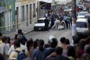 In this Nov. 19, 2013 photo, people watch forensic workers carry away the body of taxi driver Benjamin Alvarez Moncada in downtown Tegucigalpa, Honduras. The 68-year-old taxi driver known as 