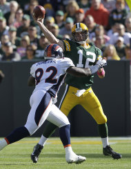 Aaron Rodgers (12), quarterback de los Packers de Green Bay, realiza un pase ante la presión del defensive end Elvis Dumervil (92), de los Broncos de Denver, en la primera mitad del juego del domingo 2 de octubre del 2011, en Green Bay, Wisconsin. (Foto AP/Darron Cummings)