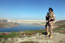 An Iraqi Kurdish Peshmerga stands guard near the Mosul Dam