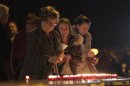 People light candles during a memorial service at the 't Stekske school in Lommel, Belgium on Thursday, March 15, 2012. A coach accident in Switzerland on Wednesday left 28 dead, including 22 children from Belgium traveling home after a skiing holiday, local police said Wednesday. Police said 24 children were injured when their Belgian bus crashed into the wall of a motorway tunnel near Sierre, south of Bern, late Tuesday. The cause of the crash on the straight stretch of road was not immediately clear. (AP Photo/Virginia Mayo)
