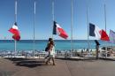 People pass French flags lowered at half-mast in Nice on July 16, 2016, following the deadly Bastille Day attack