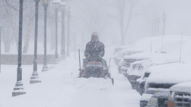 A man clears snow from the sidewalks around Friends University in Wichita, Kan. as heavy snow falls on Wednesday morning, Feb. 20, 2013. A large winter storm moved in over the early morning hours and is expected to last until Thursday evening. (AP Photo/The Wichita Eagle, Travis Heying)