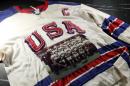 A picture of the 1968 U.S. Olympic team sits on the game worn jersey of Herb Brooks at Heritage Auctions Thursday, Feb. 12, 2015, in Dallas. The jersey and other personal items belonging to the legendary hockey coach will be auctioned Feb. 21. (AP Photo/Tony Gutierrez)