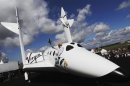 File photo of entrepreneur Branson waving a model of the LauncherOne cargo spacecraft from a window of an actual size model of SpaceShipTwo on display, after Virgin Galactic's LauncherOne announcement and news conference, at the Farnborough Airshow 2012