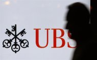 A man passes a UBS logo displayed on a screen in a window of a UBS bank building in Bern February 6, 2012. UBS will present their annual full year results for 2011 on February 7, 2012. REUTERS/Pascal Lauener
