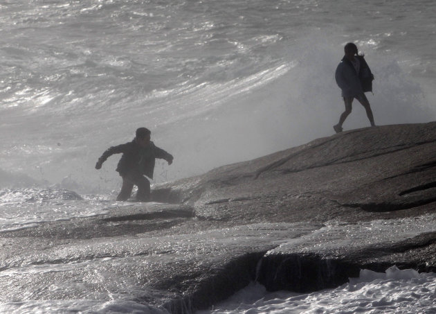 A man and his daughter scramble across the shoreline rocks after being hit by a wave on Sunday, Aug. 28, 2011 in Peggy's Cove, Nova Scotia. Atlantic Canada is experiencing increased wind and rain as t