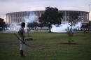 Native Brazilian stands in front of the Mane Garrincha soccer stadium as police use tear gas in Brasilia