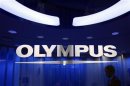 Man passes behind a logo of Japan's Olympus Corp at the company headquarters in Tokyo