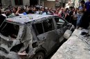In this photo released by the Syrian official news agency SANA, Syrians investigate a damaged vehicle after two suicide bombings hit security compounds in Damascus, Syria, Wednesday, June 23, 2013. Syrian activists and state media say several have been killed in two suicide bombing attacks on security compounds in the capital, Damascus. The state-run news agency says three suicide bombers blew themselves up while trying to break into the Rukneddine police station. (AP Photo/SANA)