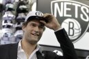 Brooklyn Nets basketball player Brook Lopez tries on a hat with the new Nets' logo during a news conference to unveil the new logos in the Brooklyn borough of New York, Monday, April 30, 2012. The Nets will be moving from New Jersey to the new Barclays Center in Brooklyn, New York for the 2012-2013 NBA basketball season. (AP Photo/Seth Wenig)