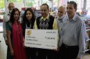 This June 2012 photo provided by WMAQ-TV in Chicago shows Urooj Khan, center, holding a ceremonial check in Chicago for $1 million as winner of an Illinois instant lottery game. At left, is Khan's wife, Shabana Ansari. Khan, 46, who owned several dry cleaning operations and some real estate, died suddenly on July 20, 2012, just days before he was to collect his winnings. Khan's death has been ruled a homicide. Court records show that Ansari has battled with his siblings over control of his estate, including his $425,000 prize money. A Cook County judge on Friday, Jan. 11, 2013, approved the exhumation of Khan's body. (AP Photo/Courtesy of WMAQ-TV in Chicago)