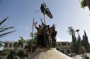 A member of al Qaeda's Nusra Front climbs on a pole to hang the Nusra flag as others celebrate around a central square in the northwestern city of Ariha, after a coalition of insurgent groups seized the area in Idlib province