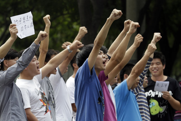 A Chinese man holds up a piece of paper with the words " Diaoyu island belongs to China, Japanese get out" as he protests with others outside the Japanese embassy in Beijing, China Tuesday, Sept. 11, 2012. Chinese government ships are patrolling near contested East China Sea islands in a show of anger after Tokyo moved to assert its control in the area. Beijing warned Monday that Japan would suffer unspecified consequences if Tokyo purchased the islands from private owners, as it formally did Tuesday.(AP Photo/Ng Han Guan)