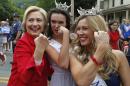 Democratic presidential candidate Hillary Rodham Clinton flexes her muscles with Miss Teen New Hampshire Allie Knault, center, and Miss New Hampshire Holly Blanchard, during a Fourth of July parade, Saturday, July 4, 2015, in Gorham, N.H. (AP Photo/Robert F. Bukaty)