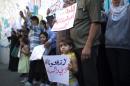 Palestinian families who fled Syria hold placards during a protest in front of the headquarters of the United Nations Relief and Works Agency (UNRWA) to demand assistance and work on October 28, 2013 in Gaza City