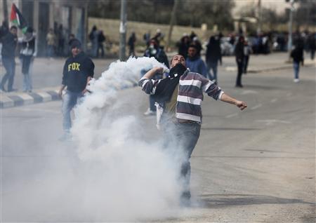 A Palestinian protester throws back a tear gas canister fired by Israeli border policemen during clashes outside Israel's Ofer prison near the West Bank city of Ramallah February 15, 2013. REUTERS/Mohamad Torokman