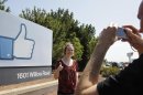 German tourists who use Facebook, take pictures outside of Facebook headquarters in Menlo Park, Calif., Friday, Aug. 17, 2012. Facebook stock is trading at $19 and has lost half its market value since its May public offering. (AP Photo/Paul Sakuma)