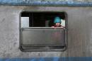 Migrant child looks out of a train window at a train station in the town of Sid