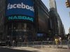 Pedestrians walk near the NASDAQ Marketsite at the start of the listing for Facebook in New York