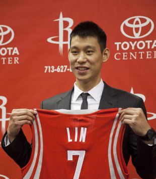 Jeremy Lin poses with his jersey during a news conference after signing a deal to play for the Rockets, in Houston