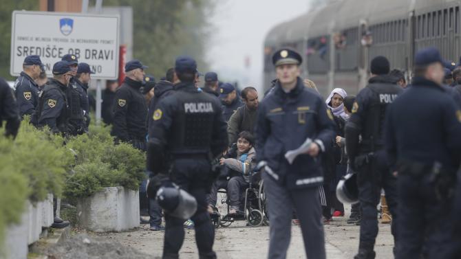 Police officers organize groups of migrants after they arrive from Croatia in Sredisce ob Dravi, Slovenia, Sunday, Oct. 18, 2015.  Hungary shut down its border with Croatia to the free flow of migrants, prompting Croatia to redirect thousands of people toward its border with Slovenia. (AP Photo/Petr David Josek)
