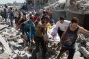 Syrians carry a body on a stretcher over the rubble after a missile fired by Syrian government forces hit a residential area in the Maghayir district of Aleppo on July 21, 2015