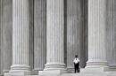 FILE - This Oct. 7, 2014, file photo shows a police officer dwarfed amid the marble columns of the U.S. Supreme Court in Washington. Anthony Elonis claimed he was just kidding when he posted a series of graphically violent rap lyrics on Facebook about killing his estranged wife, shooting up a kindergarten class and attacking an FBI agent. But his wife didn't see it that way. Neither did a federal jury. In a far-reaching case that probes the limits of free speech over the Internet, the Supreme Court on Monday is considering whether Elonis' Facebook posts, and others like it, deserve protection under the First Amendment. (AP Photo/J. Scott Applewhite, File)