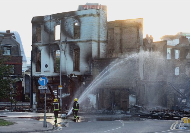 Fire fighters douse a burnt out building in Croydon, south London following a third night of unrest on the streets of London Tuesday Aug. 9, 2011. A wave of violence and looting raged across London an