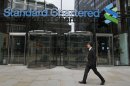 A man walks by the headquarter of Standard Chartered bank in the City of London, Tuesday, Aug. 7, 2012. Shares in Standard Chartered PLC dropped sharply on Tuesday as investors reacted to U.S. charges that the bank was involved in laundering money for Iran. The charges against Standard Chartered were a shock for a bank which proudly described itself recently as "boring." (AP Photo/Sang Tan)
