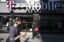 FILE - This Sept. 12, 2012 file photo shows a man using a cellphone as he passes a T-Mobile store in New York. T-Mobile USA knowingly made hundreds of millions off its customers in bogus charges, a federal regulator alleged Tuesday in a complaint that is likely to damage the reputation of a household name in wireless communications. In its complaint filed in federal court, the Federal Trade Commission claimed that T-Mobile billed consumers for subscriptions to premium text services such as $10-per-month horoscopes that were never authorized by the account holder. The FTC alleges that T-Mobile collected as much as 40 percent of the charges, even after being alerted by other customers that the subscriptions were scams. (AP Photo/Mark Lennihan, File)