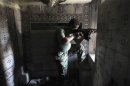 A Free Syrian Army fighter aims weapon as he takes position inside house in city of Aleppo