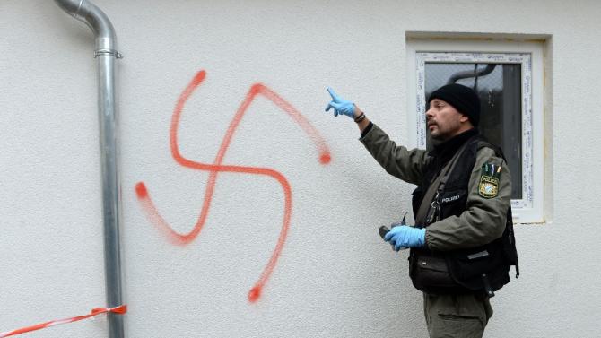 A police officer inspects a swastika which was sprayed on a refugee centre during a 2014 arson attack in Vorra, southern Germany