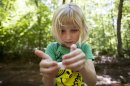 Lori Anne Madison, 6, of Lake Ridge, Va., looks at a snail she collected while playing with friends in McLean, Va., on Friday, May 11, 2012. Lori Anne is the youngest contestant in the 2012 National Spelling Bee. (AP Photo/Jacquelyn Martin)