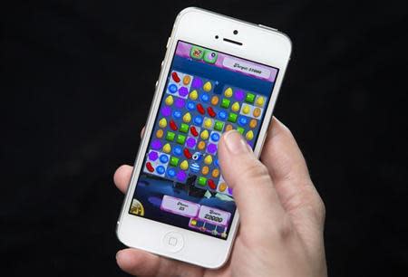 A woman poses for a photo illustration with an iPhone as she plays Candy Crush in New York
