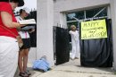 While abortion opponents pray, left, Jackson Women's Health Organization owner Diane Derzis poses at the gate of Mississippi's only abortion clinic in Jackson, Miss., Monday, July 2, 2012, after a federal judge issued a temporary restraining order Sunday, that blocked enforcement of a law that could regulate it out of business. The law would require any physician doing abortions at the clinic to be an OB-GYN with privileges to admit patients to a local hospital. (AP Photo/Rogelio V. Solis)