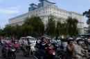 Motorcyclists ride past a newly built luxury shopping center in Ho Chi Minh City, Vietnam, on November 20, 2013