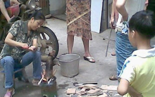 The woman could be seen roasting the puppy with people watching on including children. (Screengrab from ww.chinasmack.com)