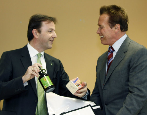 Austrian born actor and former Governor of California Arnold Schwarzenegger, right, gets gifts from Austrian Agriculture Minister Nikolaus Berlakovich, left, during a press conference in Guessing in the province of Burgenland, Austria, on Sunday, Jan. 22, 2012. Schwarzenegger visited a technological center that offers scientists options especially for the realization of projects for renewable energy. (AP Photo/Ronald Zak)