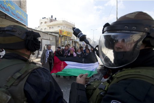 Foreign activists hold a Palestinian flag opposite Israeli security forces during clashes near Ramallah
