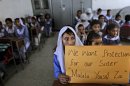 Pakistani girls display a poster while sitting at their desk, as their teacher, not shown, talks to them about 14-year-old schoolgirl Malala Yousufzai, who was shot on Tuesday by a Taliban gunman for her role in promoting girls' education in the Swat Valley where she lives, in a school in Islamabad, Pakistan, Friday, Oct. 12, 2012. A Pakistani military spokesman says Yousufzai is in "satisfactory" condition but cautions that the next few days will be critical. (AP Photo/Muhammed Muheisen)