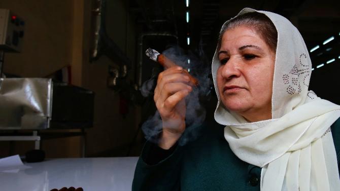 Employee Um Ali takes a smoke break at a factory producing Syria&#39;s first locally made cigars in the northwestern province of Latakia