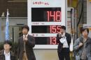 People wait to cross a street in front of a Shell filling station with the electric indicator showing a liter of regular gas price, top, at 148 yen, or $1.25, per liter (554 yen, or $4.69 per gallon) in Tokyo Friday, Nov. 28, 2014. A renewed plunge in oil prices is a worrying sign of weakness in the global economy that could shake governments dependent on oil revenues. It is also a panacea as pump prices fall, giving individuals more disposable income and lowering costs for many businesses. Partly because of the shale oil boom in the U.S., the world is awash in oil but demand from major economies is weak so prices are falling. The latest slide was triggered by OPEC's decision Thursday to leave its production target at 30 million barrels a day. Member nations of the cartel are worried they'll lose market share if they lower production. (AP Photo/Koji Sasahara)