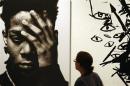 A woman looks at a work by late Haitian-American Jean-Michel Basquiat at an exhibition in Milan